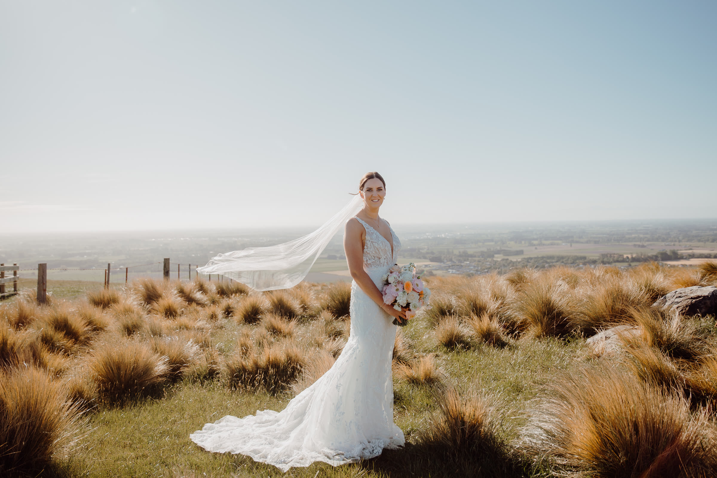 Bride with a flowing veil in the Canterbury tussock hills — wedding dress alterations by Sarah Stoute Bespoke